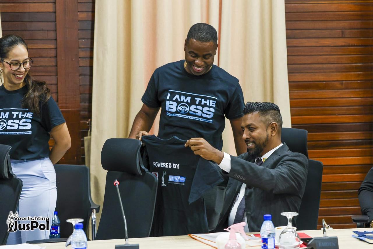 Purcy Landveld overhandigt een BOSS-campagneshirt aan minister Harish Monorath